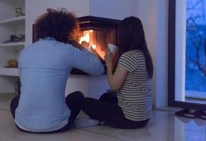 happy multiethnic couple sitting in front of fireplace photo