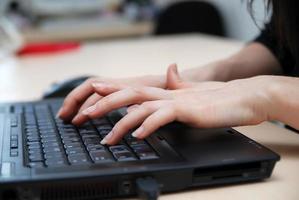 manos de mujer escribiendo en el teclado de la computadora portátil foto