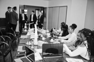 equipo de negocios multirracial que aborda la reunión alrededor de la mesa de juntas. foto