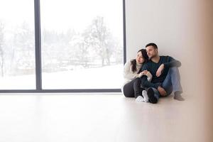 multiethnic couple sitting on the floor near window at home photo