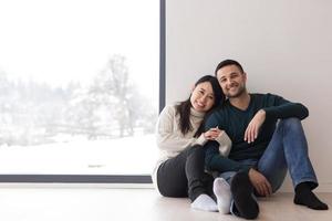 multiethnic couple sitting on the floor near window at home photo