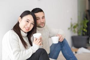 pareja multiétnica disfrutando del café matutino junto a la ventana foto