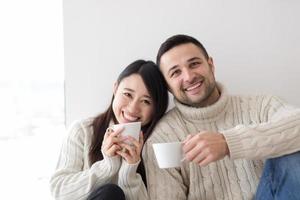 pareja multiétnica disfrutando del café matutino junto a la ventana foto