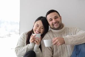 pareja multiétnica disfrutando del café matutino junto a la ventana foto