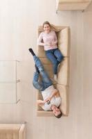 Young couple on the sofa watching television top view photo