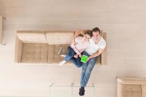 young couple in living room using tablet top view photo