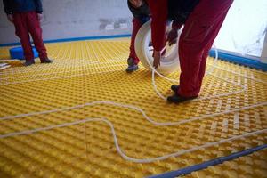 workers installing underfloor heating system photo