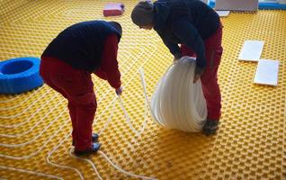 workers installing underfloor heating system photo