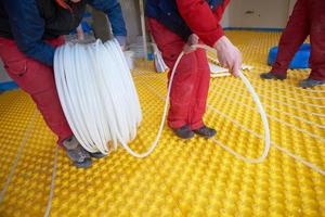 workers installing underfloor heating system photo