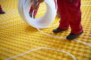 workers installing underfloor heating system photo