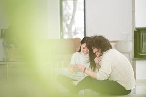 multiethnic couple using tablet computer in front of fireplace photo