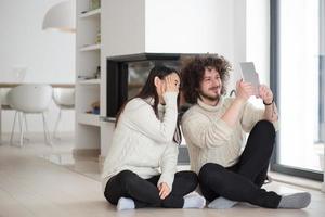 multiethnic couple using tablet computer in front of fireplace photo