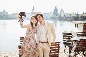 Outdoor shot of happy woman and man embrace each other and pose for making selfie, have stroll near wonderful scenery, being in good mood, enjoys nice weather. People and leisure time concept photo