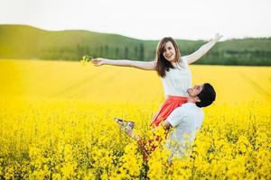el retrato de una feliz pareja familiar joven siente felicidad y libertad, posan juntos en el prado amarillo contra el cielo azul, demuestra positividad y verdadera relación. jovenes romanticos al aire libre foto