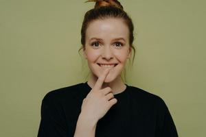 cute thoughtful teenage girl biting lower lip while posing in studio photo