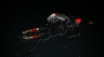 triathlon athlete swimming in dark night  wearing wetsuit photo