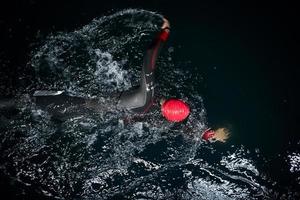 triathlon athlete swimming in dark night  wearing wetsuit photo