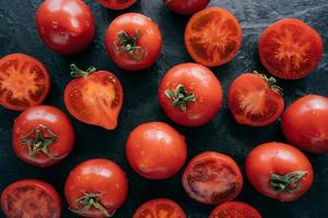 vista superior de tomates rojos muy detallados sobre fondo negro mojados. jugosas verduras apetitosas para comer. concepto de comida vagan foto