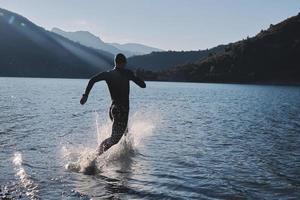 triathlon athlete starting swimming training on lake photo