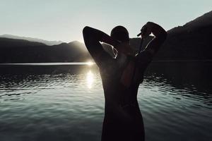 triathlon athlete starting swimming training on lake photo