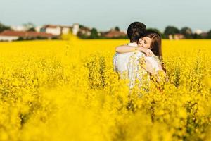 Passionate affectionate couple embrace each other, miss very much as havent seen for long time, spend wonderful summer day outdoor in yellow field. Romantic female and male hug with great love photo