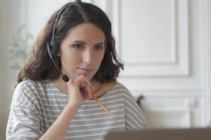 Focused entrepreneur in headphones attentively listens educational vebinar looking at laptop screen photo