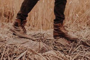 Mens brown shoes in rural territory. Unrecognizable masculine in trouses and boots. Leather old footwear. Walk outdoor photo