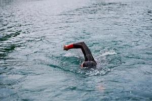 triathlon athlete swimming on lake wearing wetsuit photo