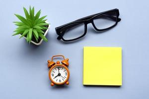 Adhesive Note with potted plant and alarm clock set at 8 o'clock. Copy space. photo