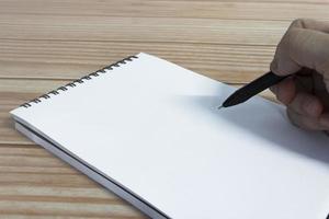 Hand with pen writing notebook on office desk table with. Copy space. photo