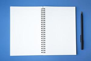 Top view of pen and notepad on blue background. Copy space. photo