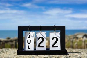 22 de julio texto de fecha de calendario en marco de madera con fondo borroso del océano. foto