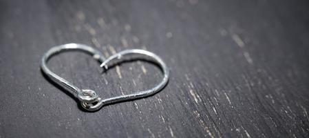 Heart-shaped fish hooks on a dark background. photo