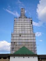 Scaffolding from planks around old bell tower. Concept of historical reenactment of repair work, access to elements of buildings of complex configuration. photo