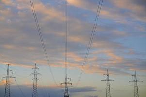 líneas eléctricas de alto voltaje con torres de alta tensión contra el fondo del cielo nublado de la noche. foto