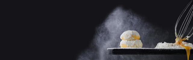 Flour pours on fresh homemade dough. Dough with spilled flour on a black background. Yeast dough for bread, rolls, pizza or pie. Copy space. photo