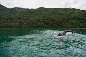 triathlon athlete swimming on lake wearing wetsuit photo