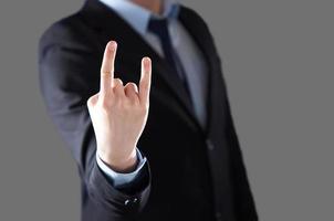 A man's hand giving the Rock and Roll sign. A man in a suit and tie in a blur. photo