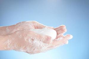 White soap in women's soapy hands on a blue background. photo