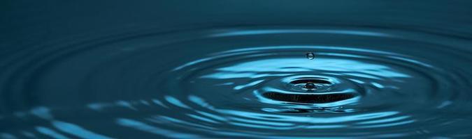 Water drop close up. Blue abstract background water drop and diverging circles. Photo with copy space.