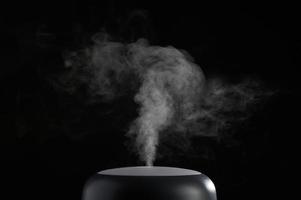 The concept of humidification of the air. Photo with copy space. Modern air humidifier on black background.