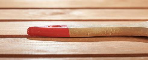 The wooden handle of the brush on the floor. Freshly painted wood surface background. photo