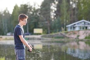 joven pescando en el lago con caña. concepto de estilo de vida de viaje vacaciones de verano. foto