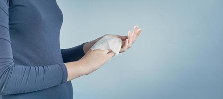 Girl cleaning her hands by using white antibacterial napkin on gray background. Photo with copy space.