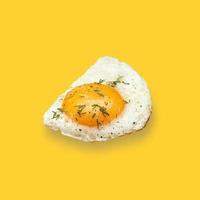 Chicken fried egg sprinkled with herbs isolated on on yellow background. Scrambled eggs close-up. photo