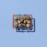 Shopping basket with quail eggs isolated on blue background. Top view. photo