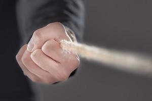 Businessman pulling a rope isolated on gray background. photo