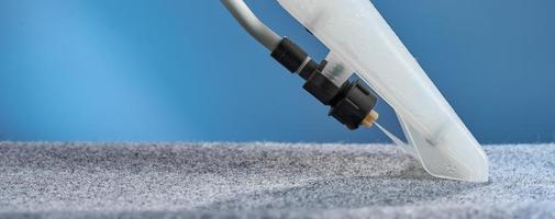 Washing carpet with vacuum cleaner close-up on a blue background. photo