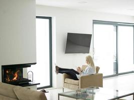 young woman using tablet computer in front of fireplace photo