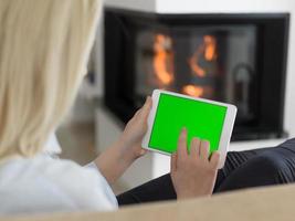 young woman using tablet computer in front of fireplace photo